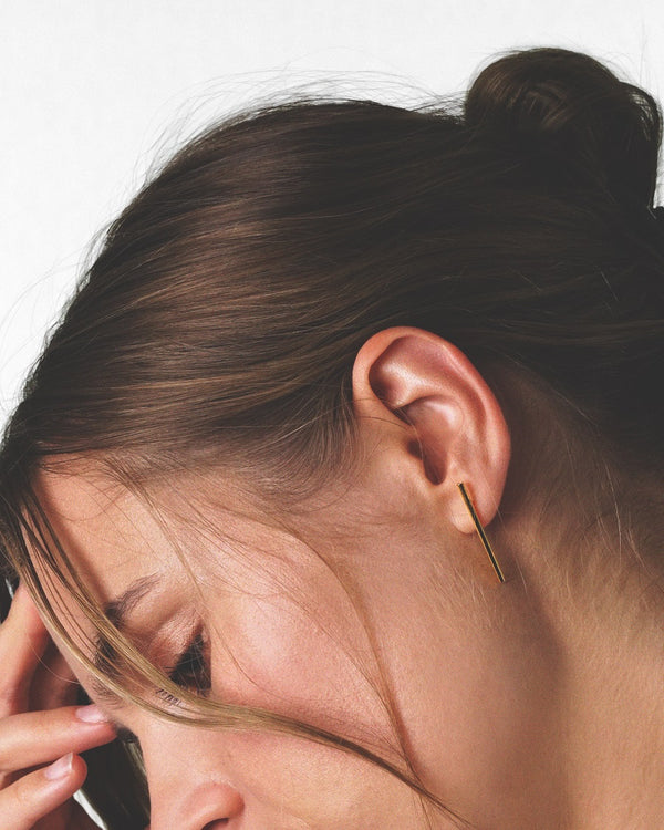 Model showcasing our gold vermeil tube earring studs with a sleek and modern design.
